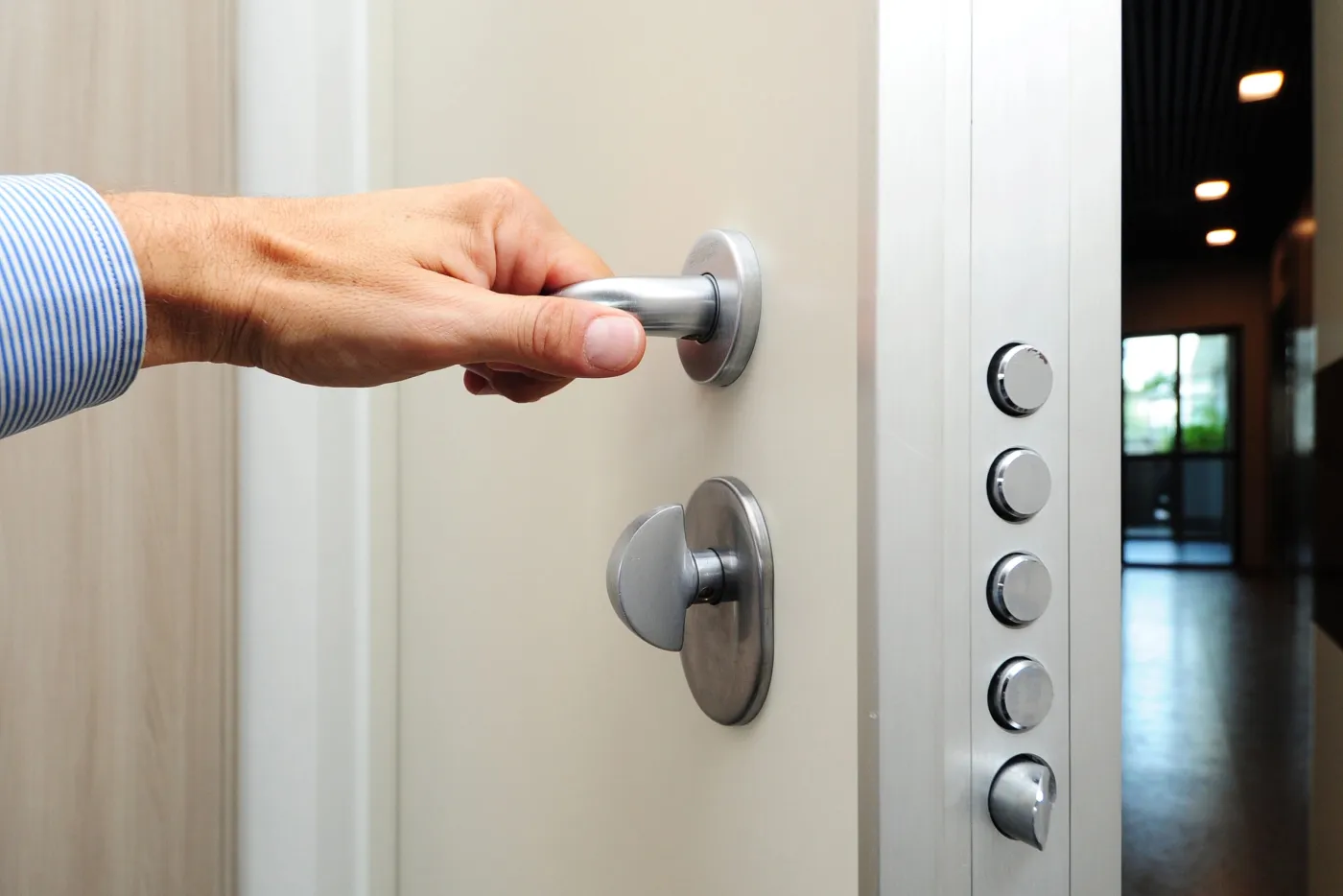 Main sur la poignée inox d'une porte d'appartement renforcée près de la place de la République, Paris 11e (75011)