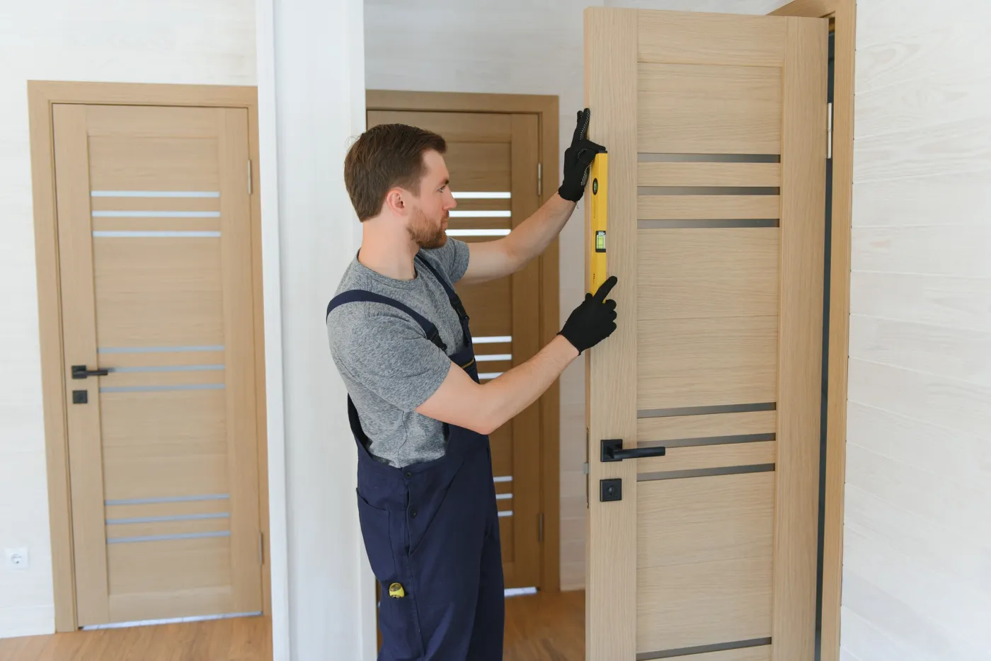 Artisan vérifiant l'alignement de portes neuves au niveau dans un immeuble du quartier République à Paris